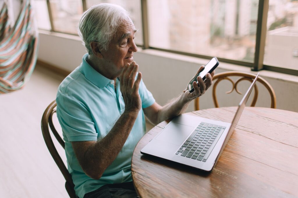 Un homme senior réfléchit devant son téléphone avant de répondre